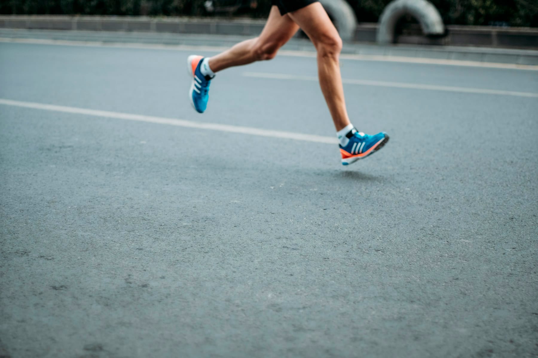 Primer plano de las piernas y los pies de una persona corriendo, mostrando la zona del tríceps sural y el talón implicados en la fascitis plantar